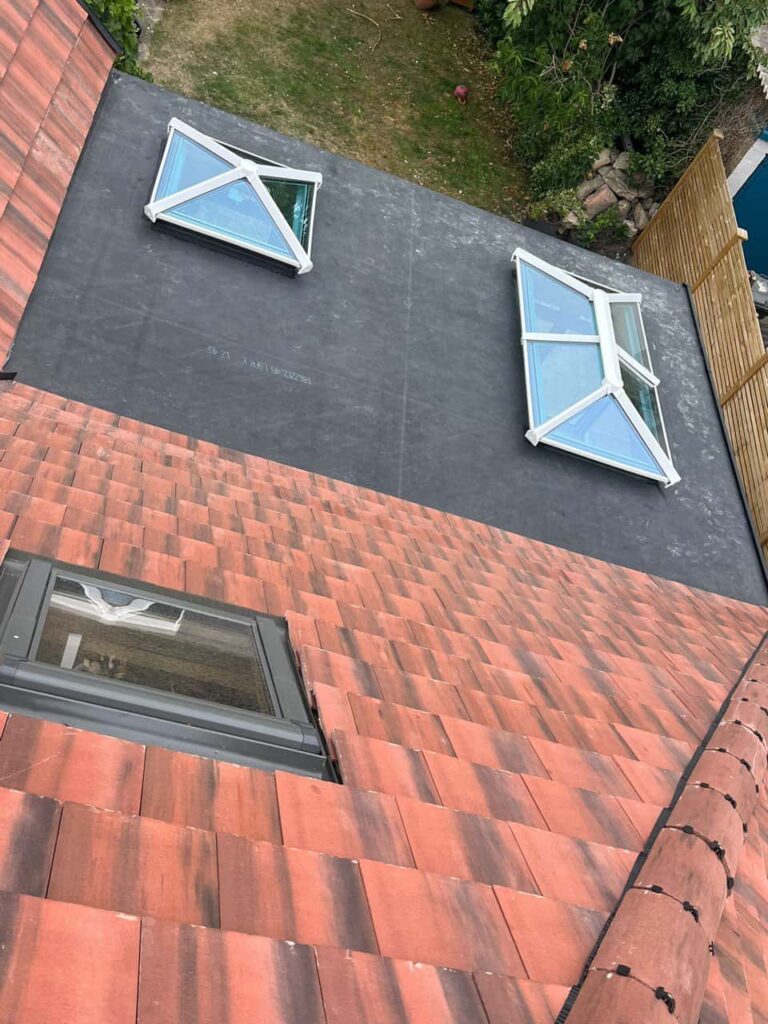 This is a photo taken from the roof ridge looking down a tiled pitched roof on to a flat roof. Works carried out by LJ Roofing Grove
